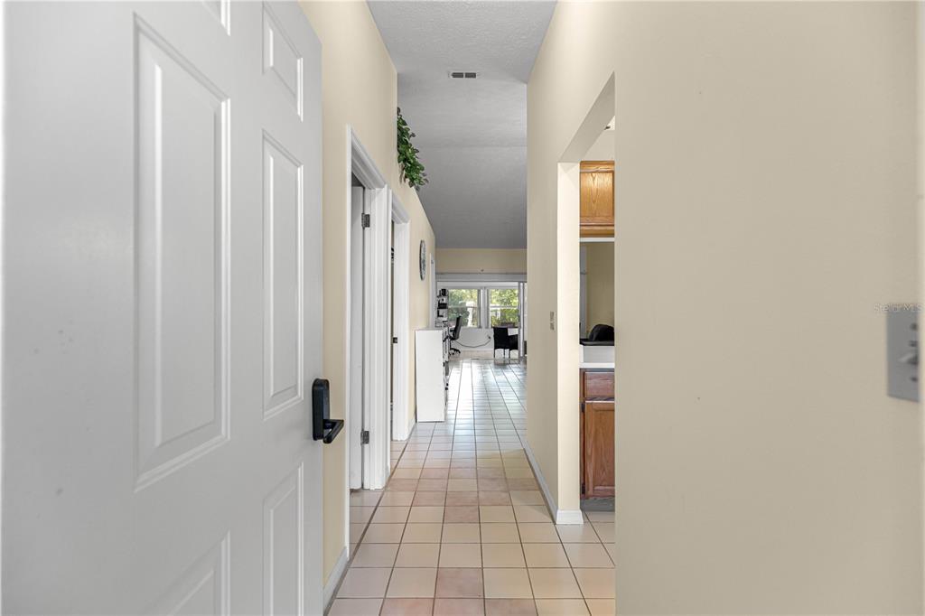 A tiled hallway leads from a doorway toward a bright living area with large windows — 10457 SW 85TH COURT, OCALA, FL