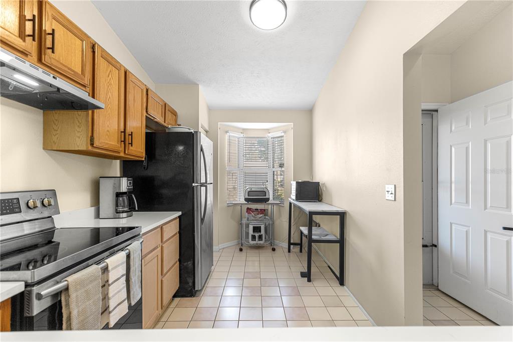 A kitchen features light wood cabinets, stainless steel appliances, and a tiled floor — 10457 SW 85TH COURT, OCALA, FL