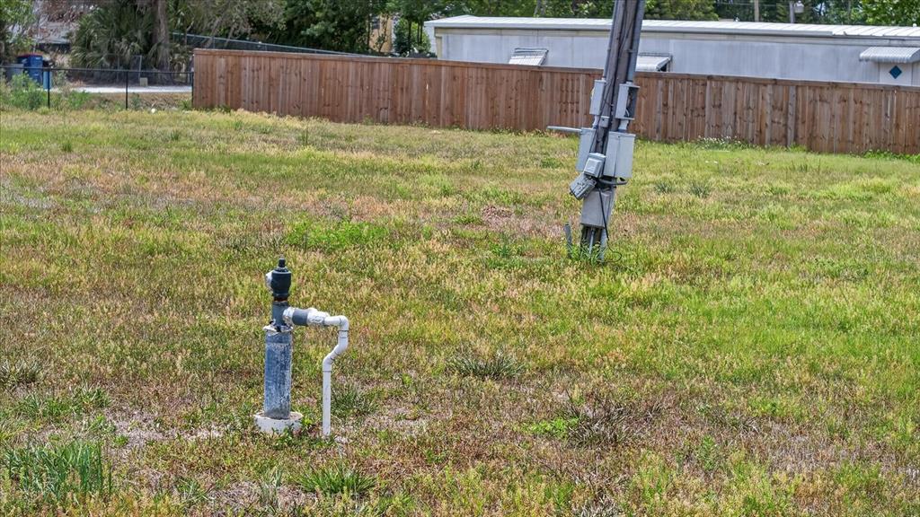 A utility pole and a water pipe stand in an open, grassy vacant lot — 4710 TROUBLE CREEK ROAD, NEW PORT RICHEY, FL