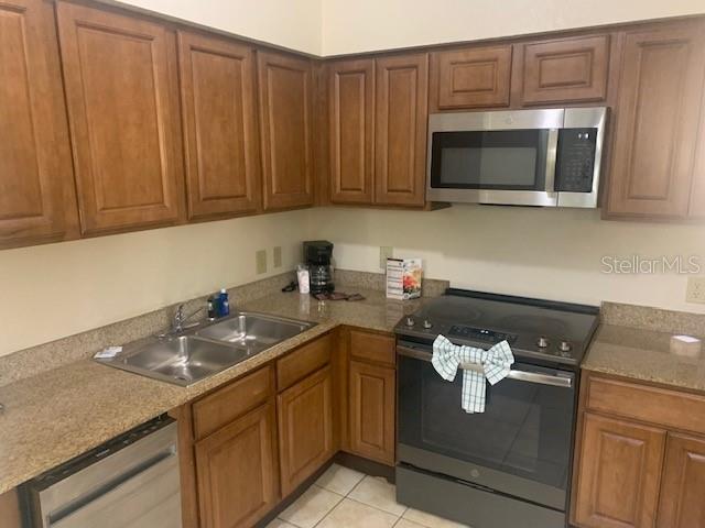 A kitchen features wood cabinets, granite countertops, and stainless steel appliances — 12539 FLORIDAYS RESORT DRIVE UNIT 112D, ORLANDO, FL