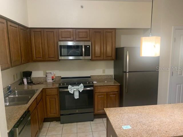 A kitchen features wood cabinets, stainless steel appliances, and a granite-topped island — 12539 FLORIDAYS RESORT DRIVE UNIT 112D, ORLANDO, FL