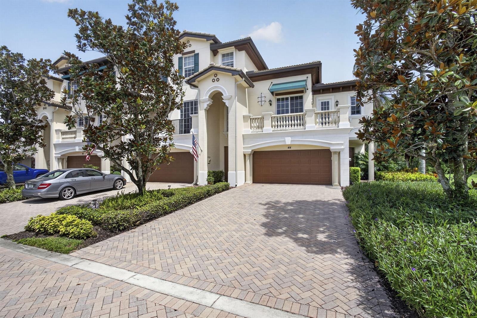 A two-story stucco townhouse features a paved driveway, two garage doors, and a balcony — 222 Tresana Boulevard # 44, Jupiter FL 33478, JUPITER, FL