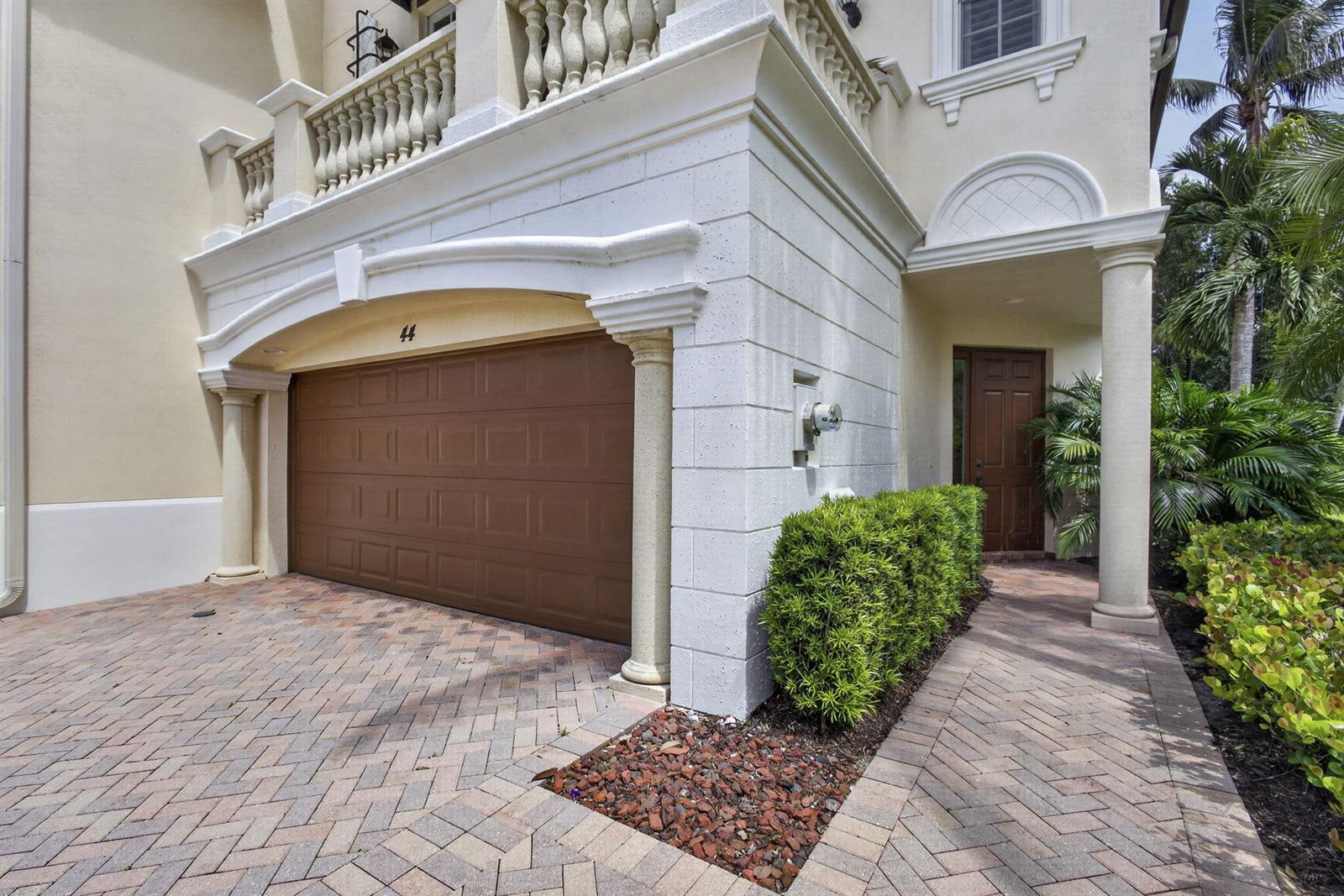 A brown garage door and a front entrance are set in a stucco building exterior — 222 Tresana Boulevard # 44, Jupiter FL 33478, JUPITER, FL