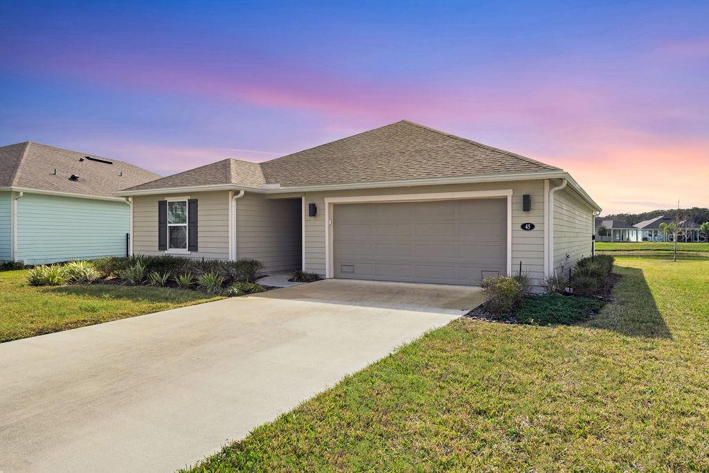 A single-story house with beige siding, a two-car garage, and a concrete driveway — 45 LAS CASITAS BOULEVARD, PALM COAST, FL