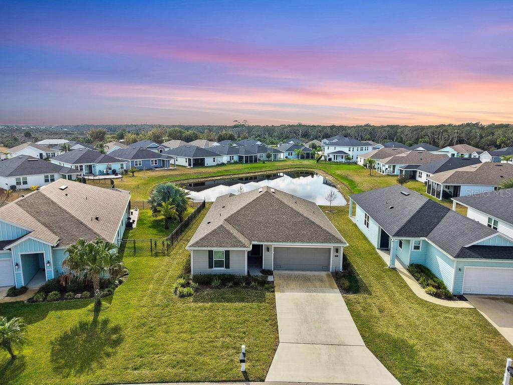 An aerial view shows a suburban neighborhood with single-family homes surrounding a central pond — 45 LAS CASITAS BOULEVARD, PALM COAST, FL