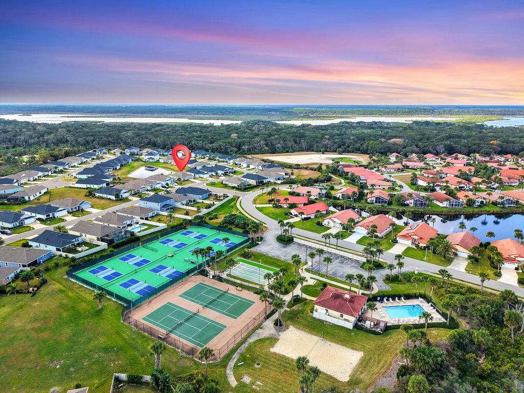 An aerial view shows a residential community with tennis courts, a pool, and houses — 45 LAS CASITAS BOULEVARD, PALM COAST, FL