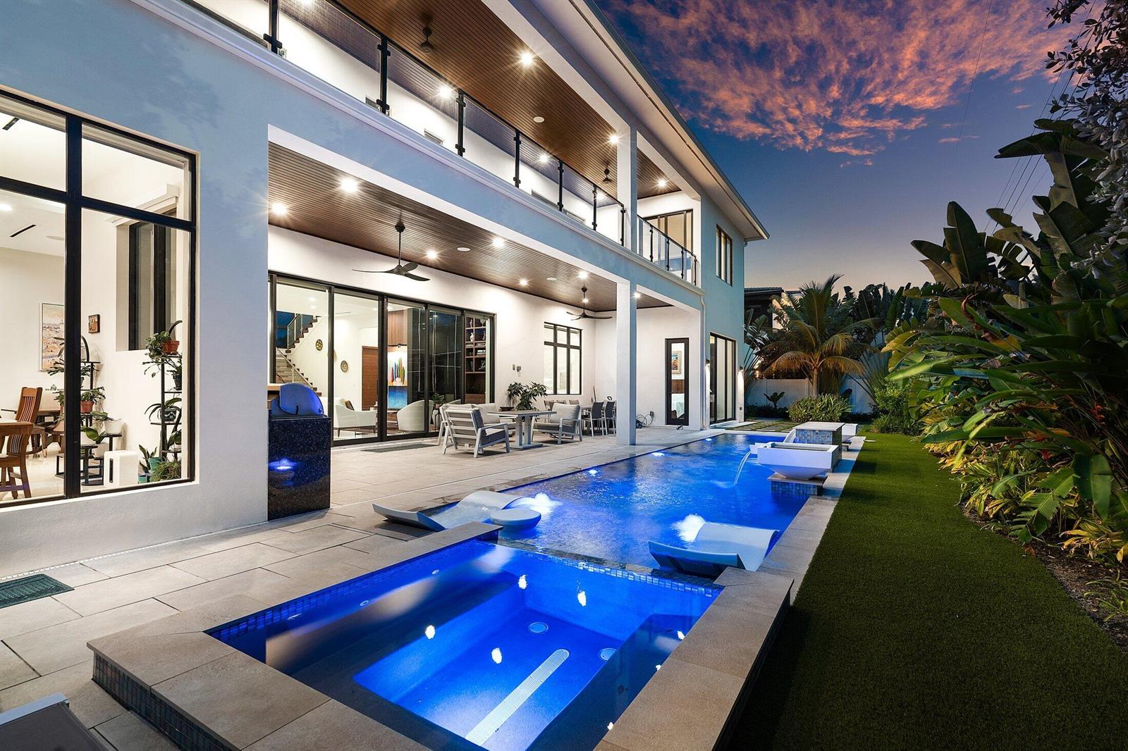 A modern two-story house with a backyard pool, spa, and covered patio at dusk — 450 NE 10th Street, Boca Raton FL 33432, BOCA RATON, FL