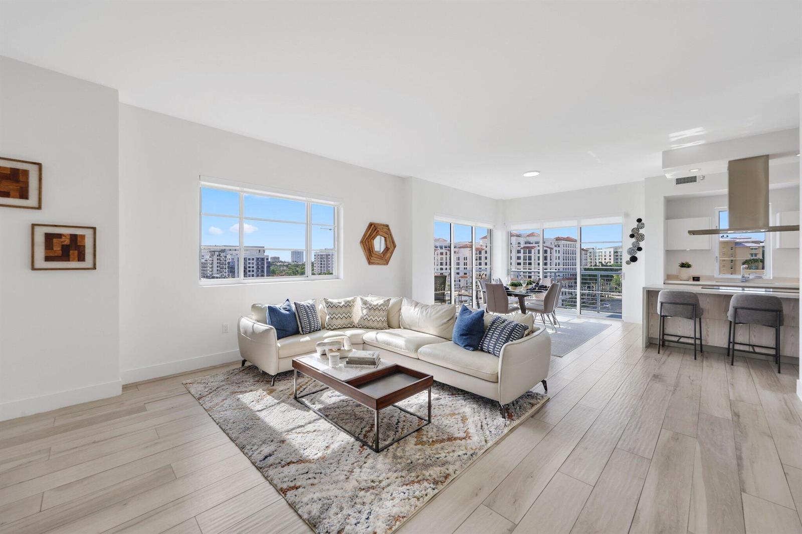 A bright living room with a white sectional sofa, wood coffee table, and open kitchen — 155 E Boca Raton Road Unit 703, Boca Raton FL 33432, BOCA RATON, FL