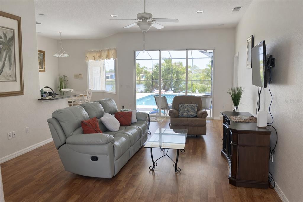 A living room features a gray sofa, a glass coffee table, and a view of a pool — 18146 AVONSDALE CIRCLE, PORT CHARLOTTE, FL