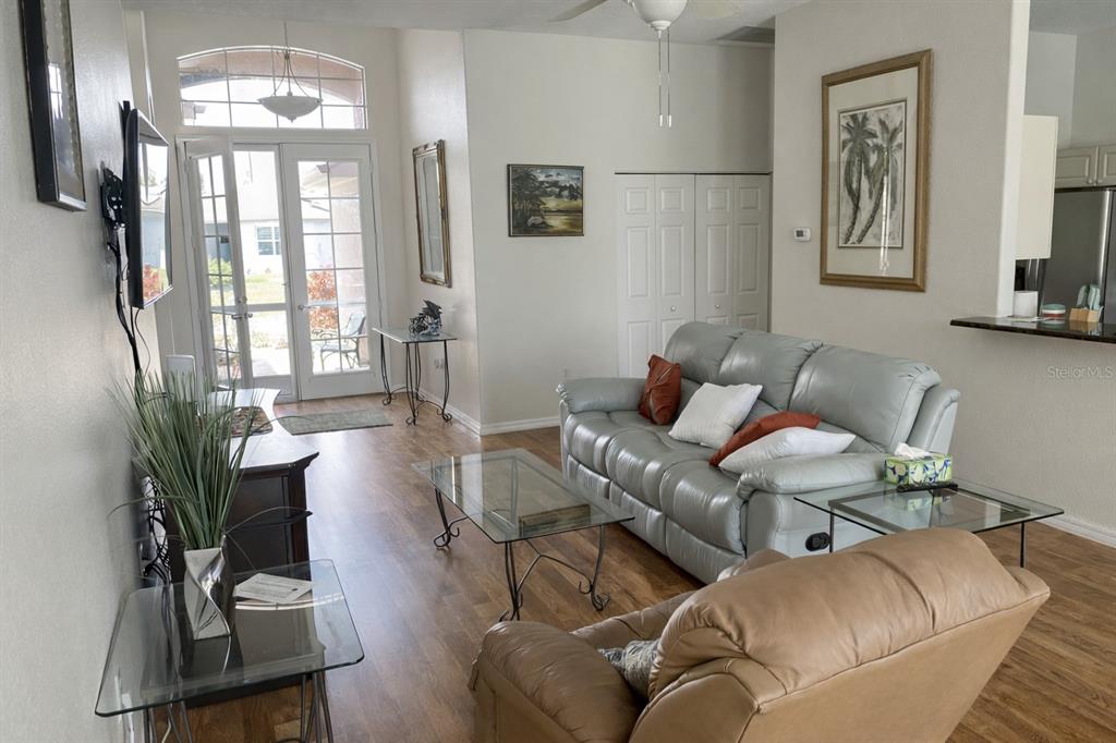 A living room features a grey leather sofa, a tan recliner, and glass-topped tables — 18146 AVONSDALE CIRCLE, PORT CHARLOTTE, FL