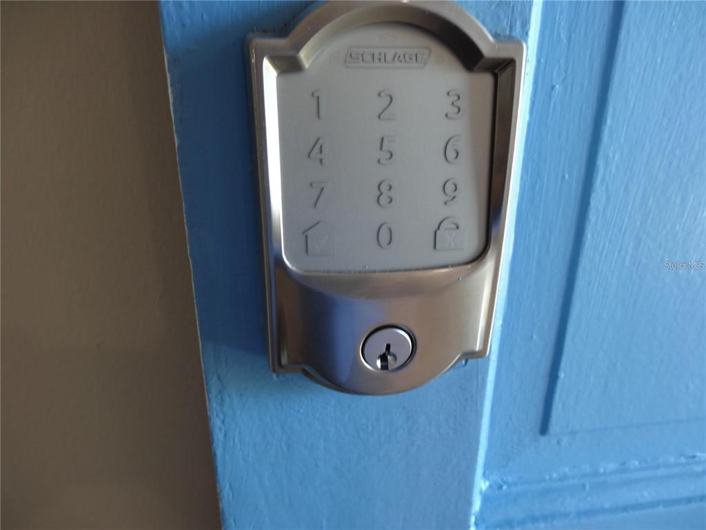 A close-up view of a silver Schlage electronic keypad deadbolt mounted on a blue door — 9715 HARRELL AVENUE UNIT 139, TREASURE ISLAND, FL
