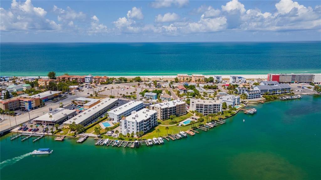 An aerial view of a coastal resort area featuring multi-story buildings, boat docks, and oceanfront — 9715 HARRELL AVENUE UNIT 139, TREASURE ISLAND, FL