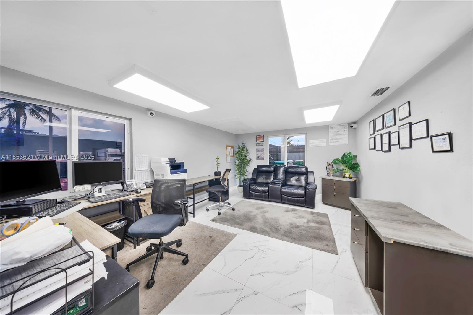 This office space features white tile floors, two desks, a black leather sofa, and windows — 2696 W 3rd Ave, Hialeah FL 33010, HIALEAH, FL