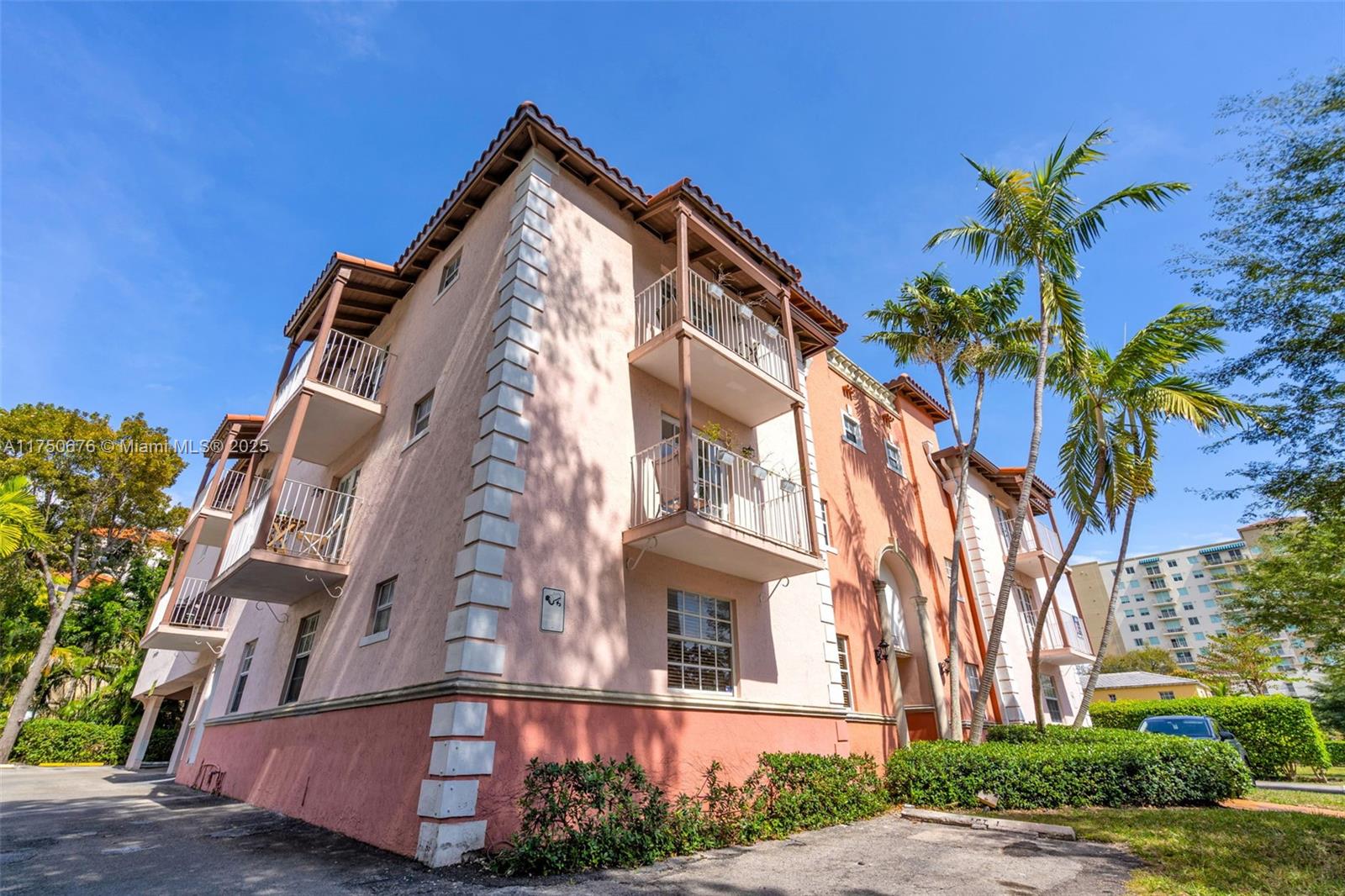 A multi-story peach-colored apartment building features white balconies and corner quoins under a blue sky — 29 Santillane Ave # 7, Coral Gables FL 33134, CORAL GABLES, FL