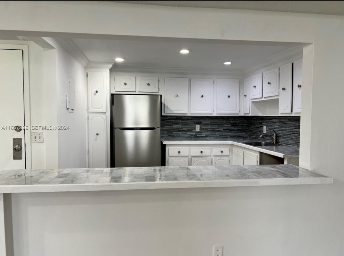 A kitchen with white cabinets, stainless steel appliances, and a gray tiled backsplash — 13499 Biscayne Blvd # 1205, North Miami FL 33181, NORTH MIAMI, FL