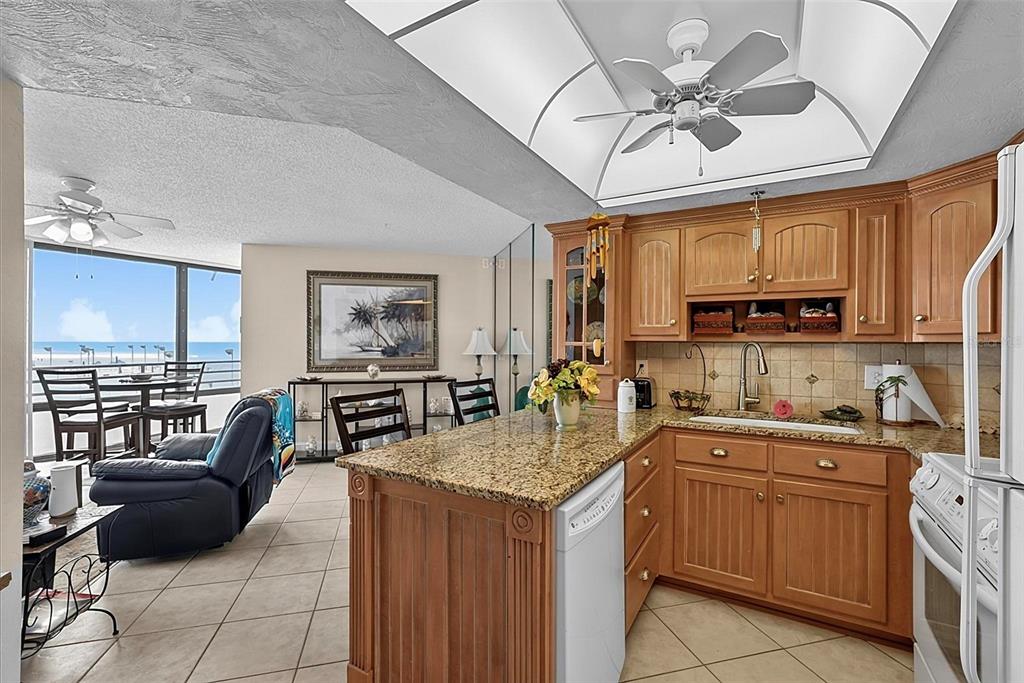 A kitchen with wood cabinets and granite countertops overlooks a living area with ocean views — 3013 S ATLANTIC AVENUE UNIT 2060, DAYTONA BEACH, FL