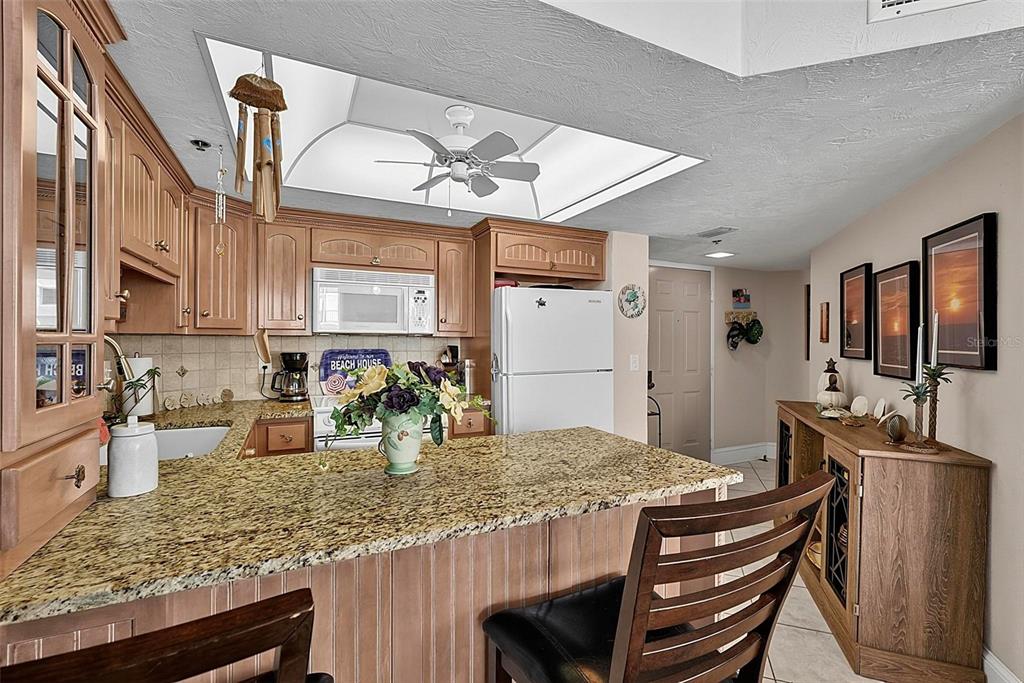 A kitchen features wood cabinets, granite countertops, a breakfast bar, and a ceiling fan — 3013 S ATLANTIC AVENUE UNIT 2060, DAYTONA BEACH, FL