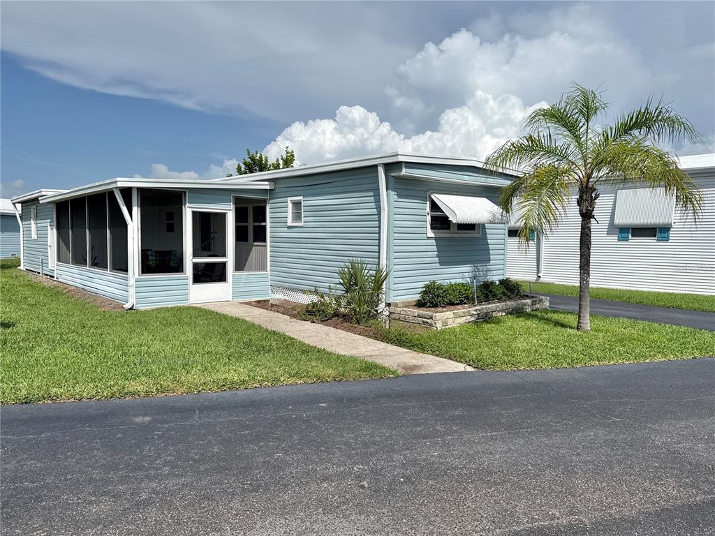 A light blue mobile home features a screened-in porch, a palm tree, and a paved driveway — 7214 MOUNT FAIRFIELD ROAD NE UNIT 527, ST PETERSBURG, FL