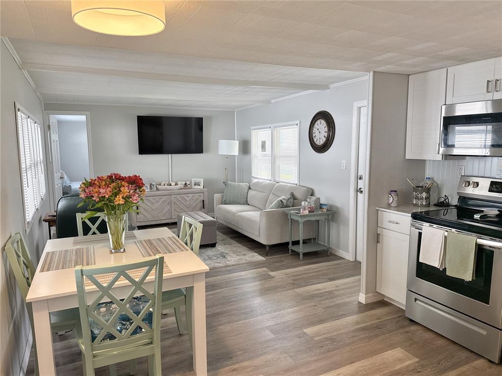 An open-concept living and dining area features light-colored walls, wood-look flooring, and a modern kitchen — 7214 MOUNT FAIRFIELD ROAD NE UNIT 527, ST PETERSBURG, FL