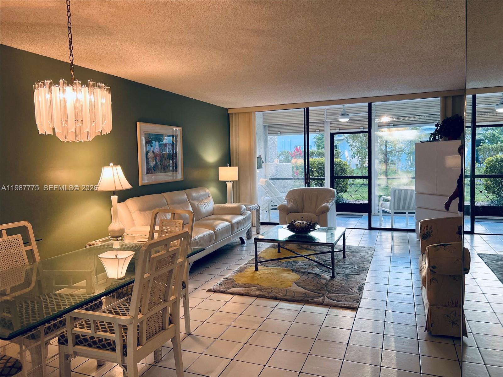 A living and dining area features white tile floors, a glass table, and a green wall — 4387 Trevi Ct # 107, Lake Worth FL 33467, LAKE WORTH, FL
