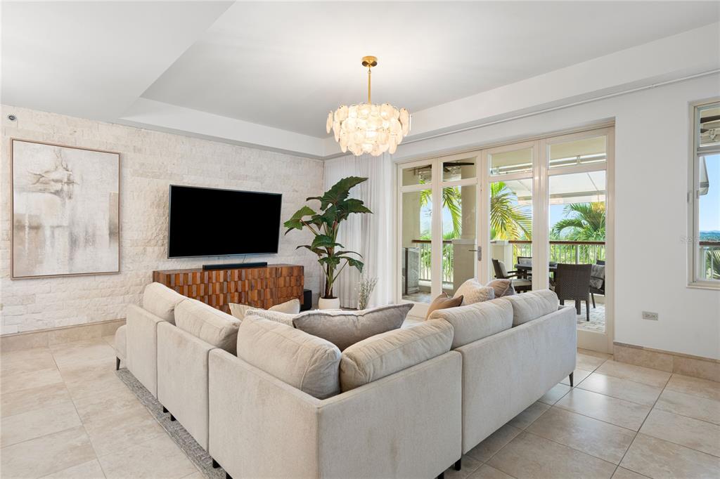A living room features a large sectional sofa, stone accent wall, and glass doors to a balcony — 500 PLANTATION VILLAGE DRIVE UNIT 3-208, DORADO, PR