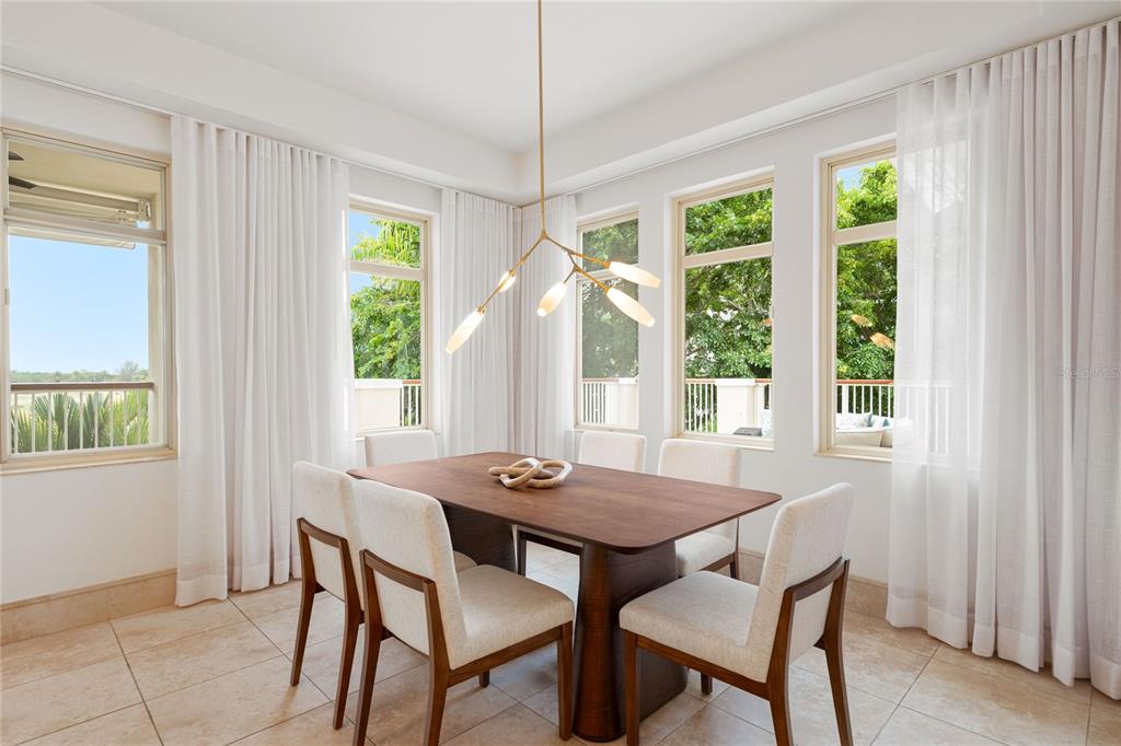 A dining room features a wooden table, six upholstered chairs, and a modern branching chandelier — 500 PLANTATION VILLAGE DRIVE UNIT 3-208, DORADO, PR