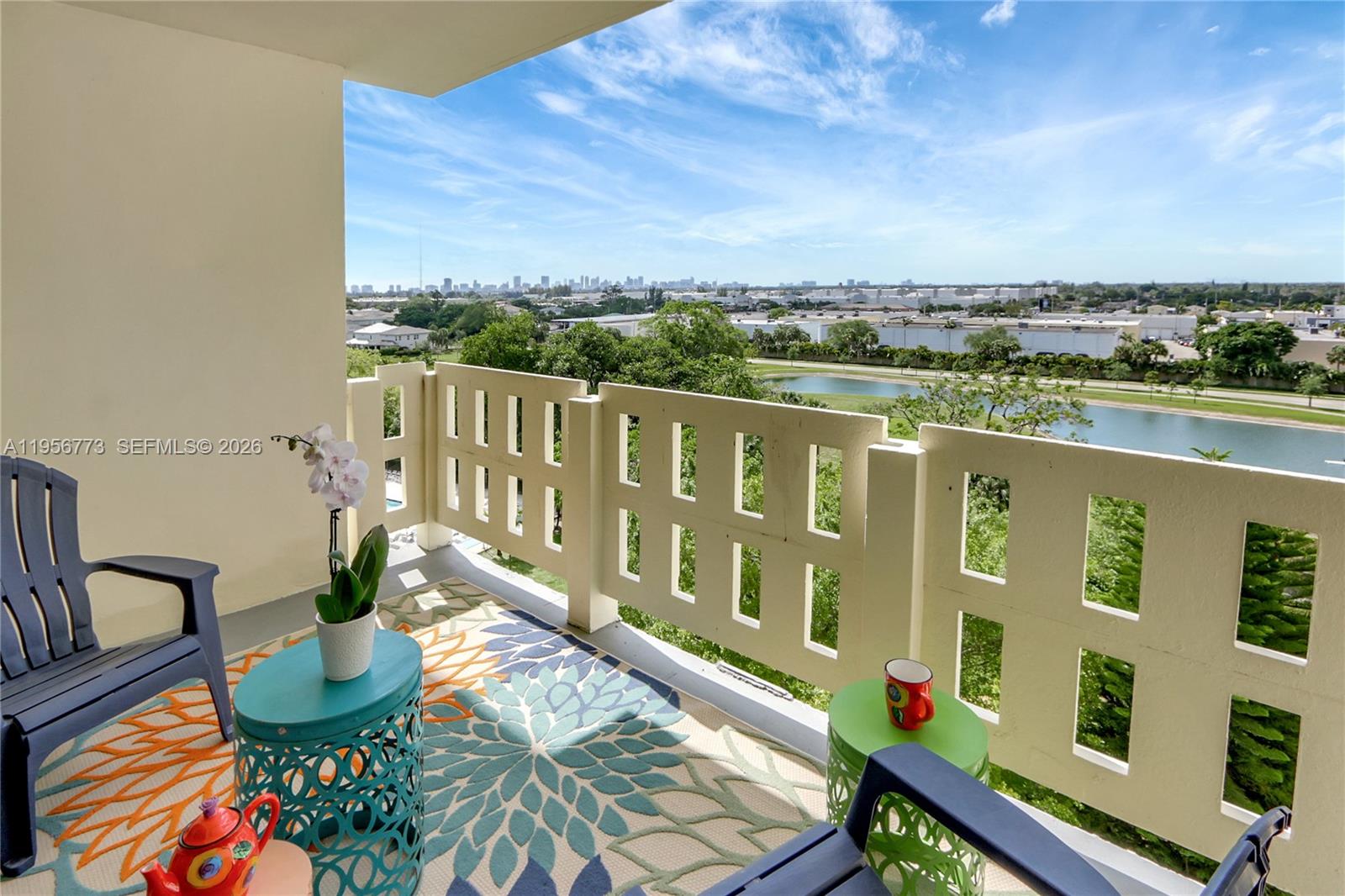 A balcony with outdoor furniture overlooks a lake and a distant city skyline — 4330 Hillcrest Dr # 807, Hollywood FL 33021, HOLLYWOOD, FL
