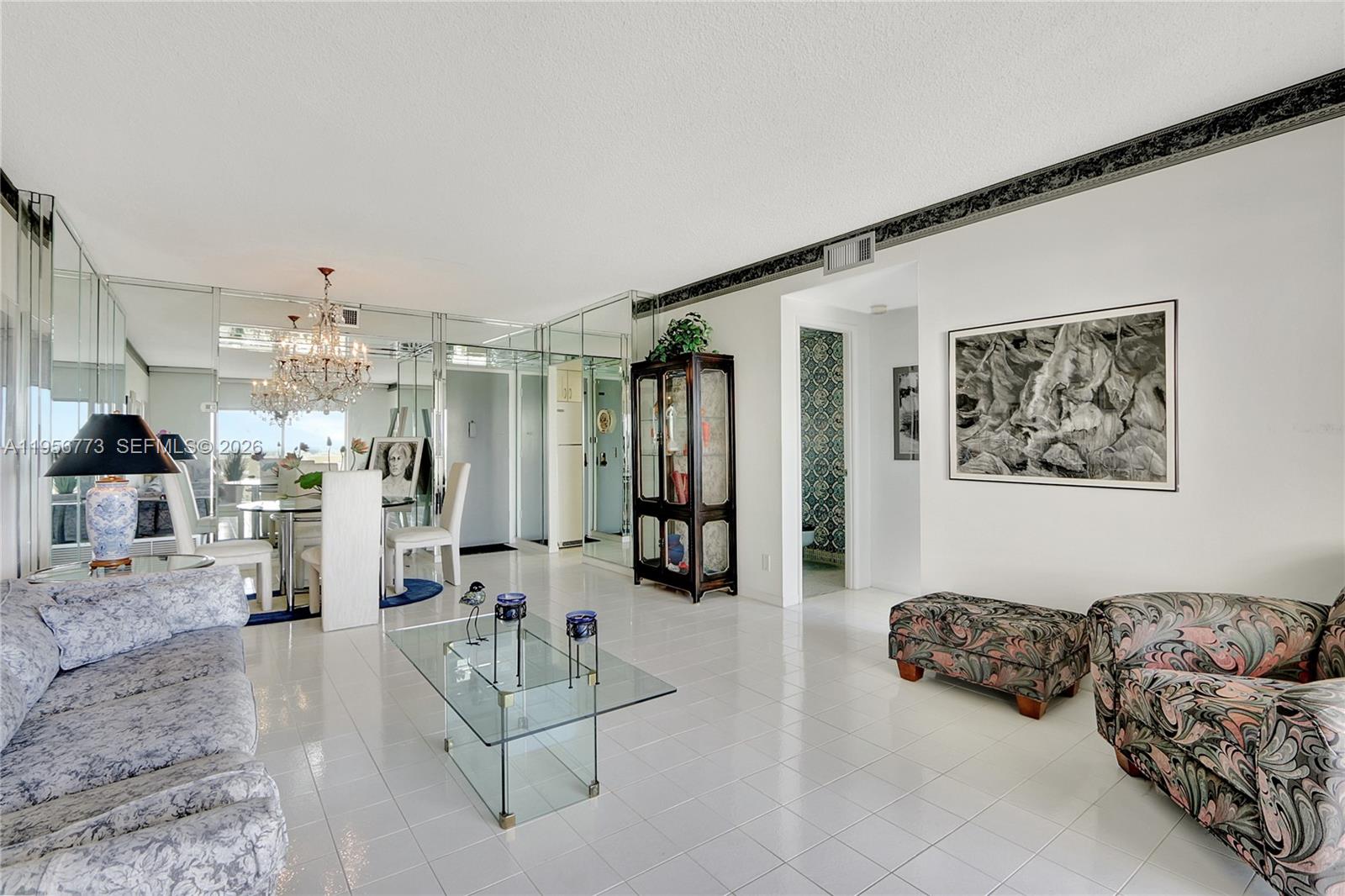 A living and dining area features white tile floors, mirrored walls, and patterned furniture — 4330 Hillcrest Dr # 807, Hollywood FL 33021, HOLLYWOOD, FL