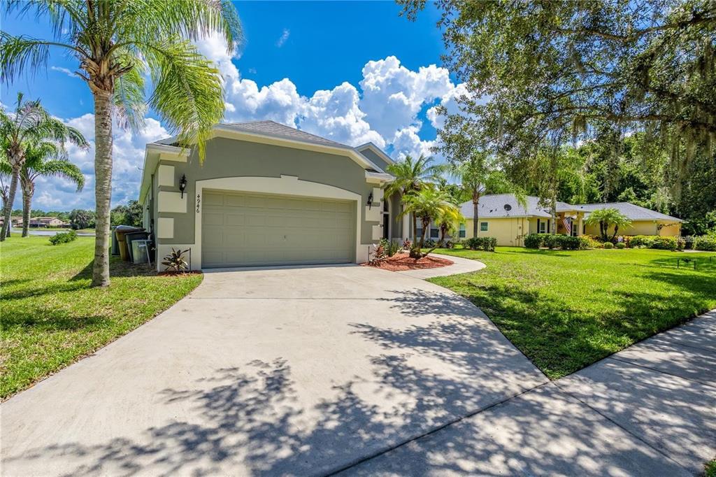 A single-story house with a two-car garage, a concrete driveway, and palm trees — 4946 LAZY OAKS WAY, ST CLOUD, FL