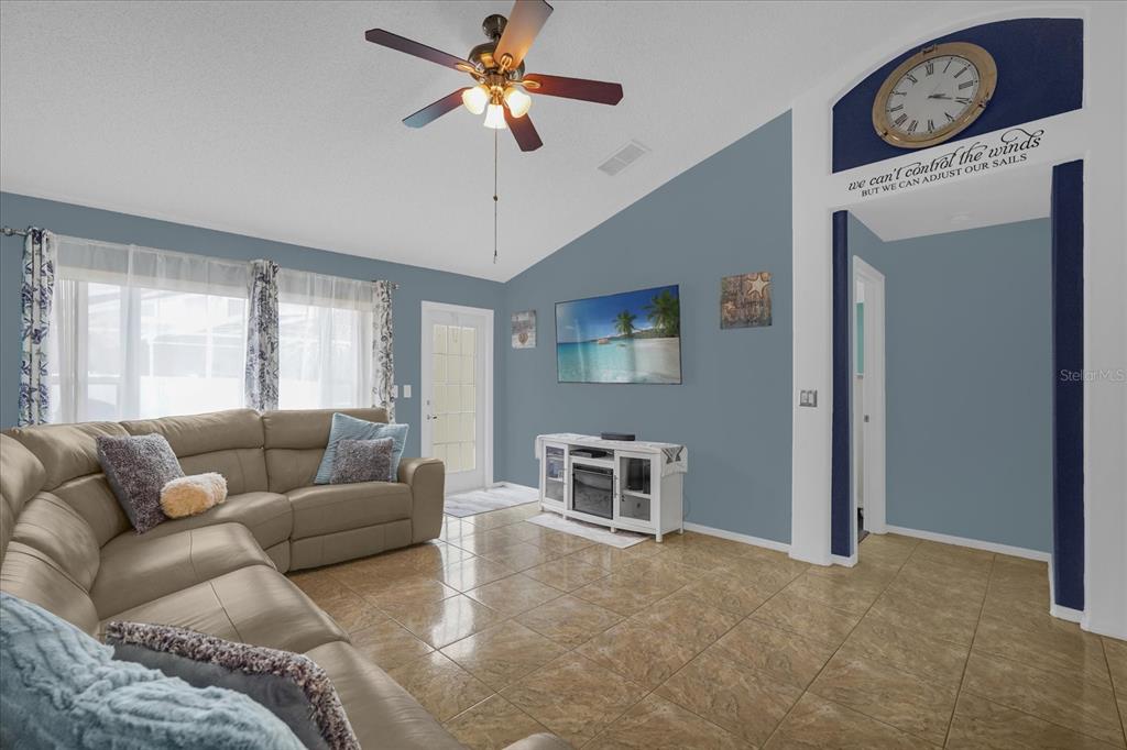 A living room features a tan sectional sofa, tile flooring, and a vaulted ceiling — 14352 SUN BAY DRIVE, ORLANDO, FL