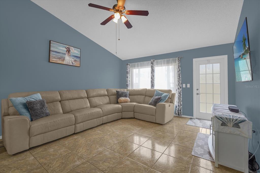 A living room features a beige sectional sofa, tile flooring, and a ceiling fan — 14352 SUN BAY DRIVE, ORLANDO, FL