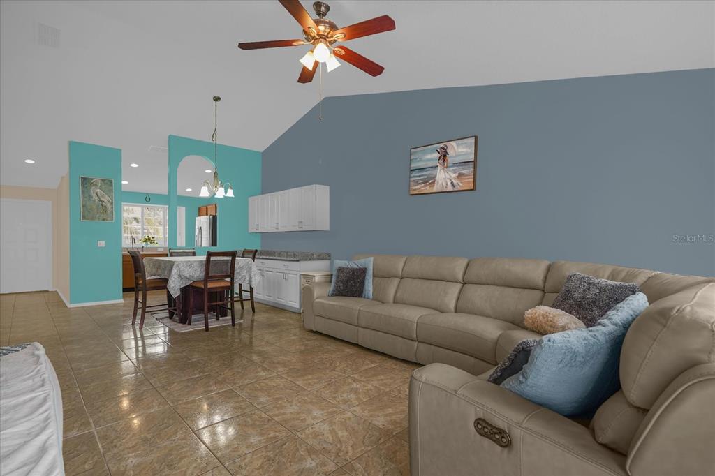 A living room with a large beige sectional sofa, tile floors, and a dining area — 14352 SUN BAY DRIVE, ORLANDO, FL