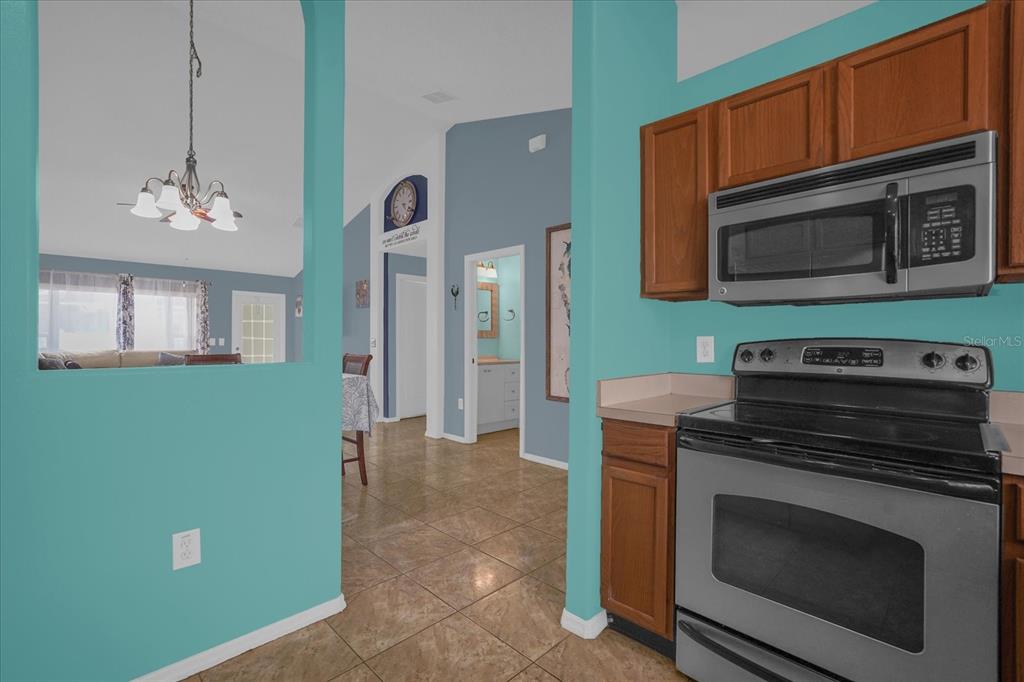 A kitchen with wood cabinets and stainless steel appliances opens into a dining area — 14352 SUN BAY DRIVE, ORLANDO, FL
