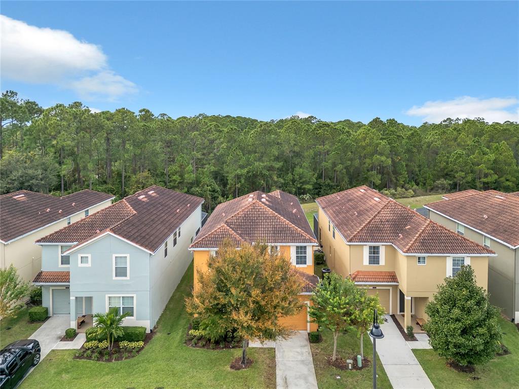 An aerial view shows three two-story suburban houses with tile roofs and adjacent driveways — 2908 BANANA PALM DRIVE, KISSIMMEE, FL