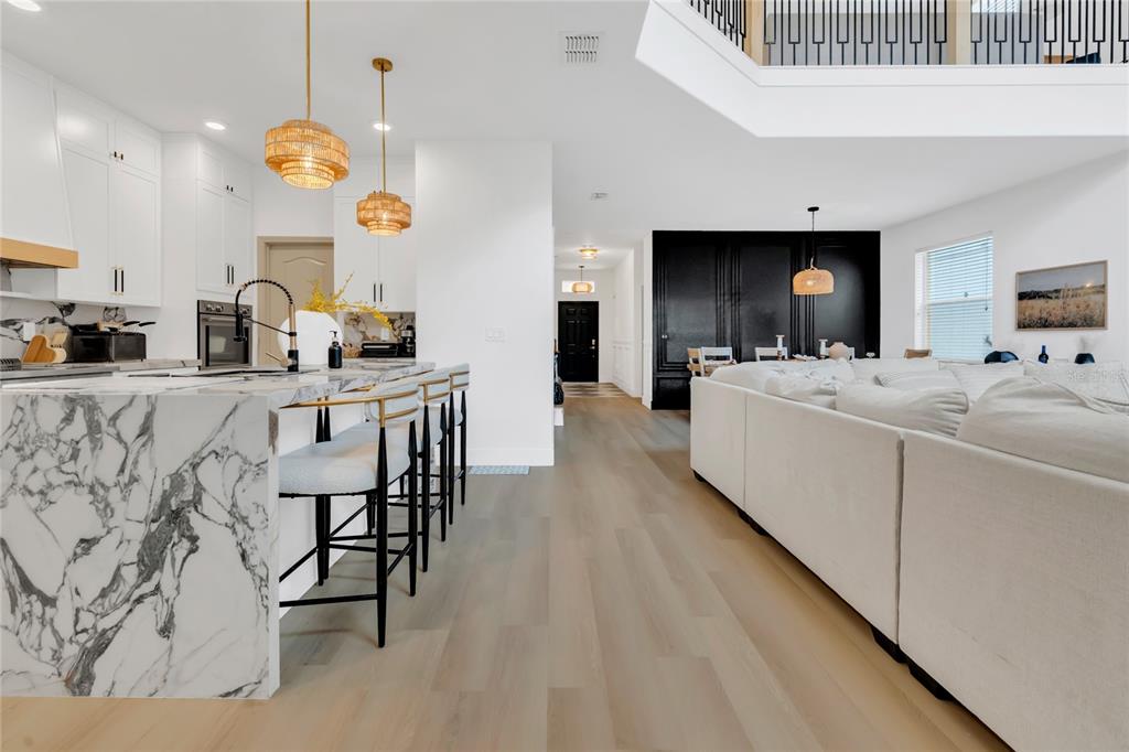 A modern open-concept kitchen and living area features a marble island and light wood floors — 2908 BANANA PALM DRIVE, KISSIMMEE, FL