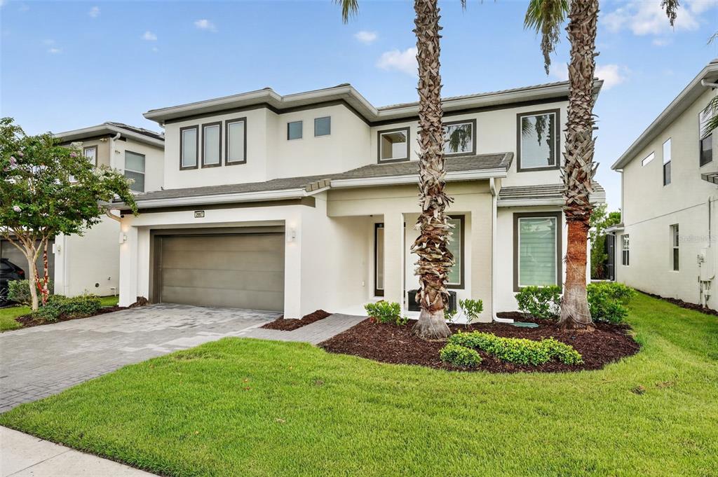 A two-story house with a two-car garage, light-colored stucco exterior, and two palm trees — 2667 CALISTOGA AVENUE, KISSIMMEE, FL