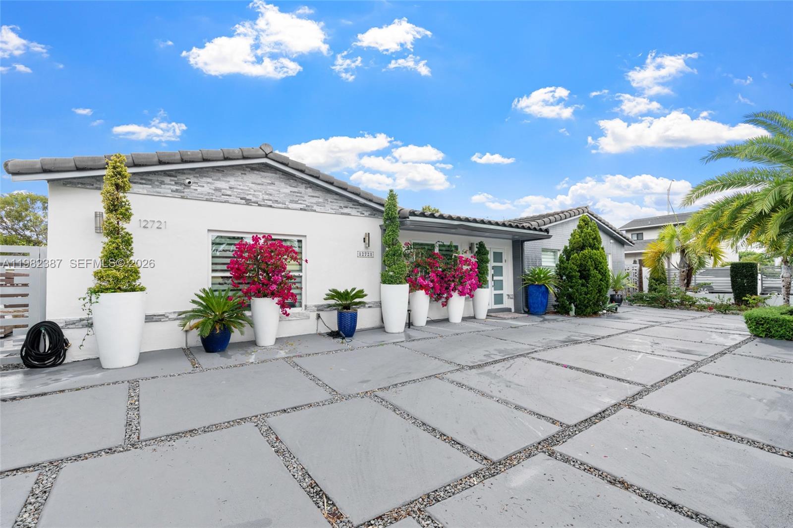 A single-story house exterior features white walls, stone accents, and a large paved driveway — 12721 SW 47th St, Miami FL 33175, MIAMI, FL
