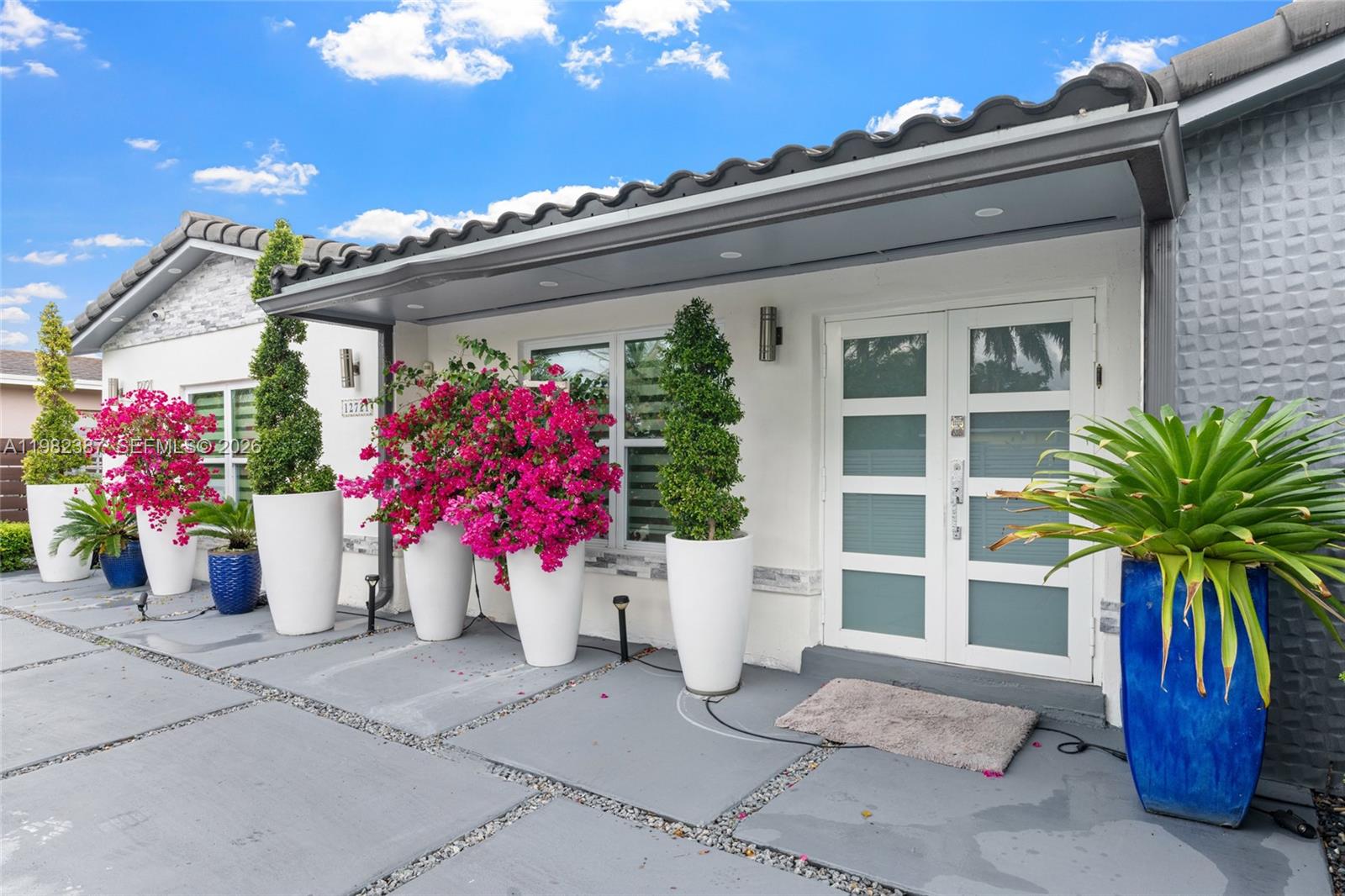 The exterior of a house features a gray patio with potted plants and double glass doors — 12721 SW 47th St, Miami FL 33175, MIAMI, FL