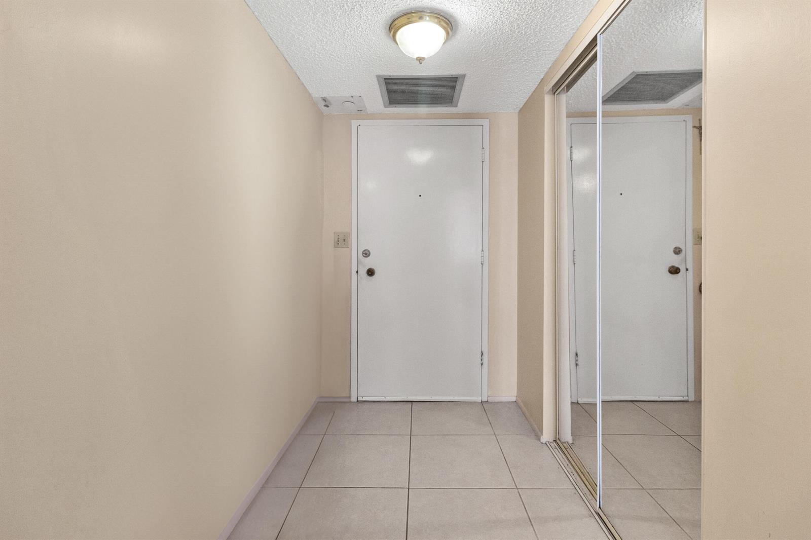 An entryway features a white door, tiled floor, and a mirrored sliding closet door — 111 N Pompano Beach Boulevard # 1507, Pompano Beach FL 33062, POMPANO BEACH, FL