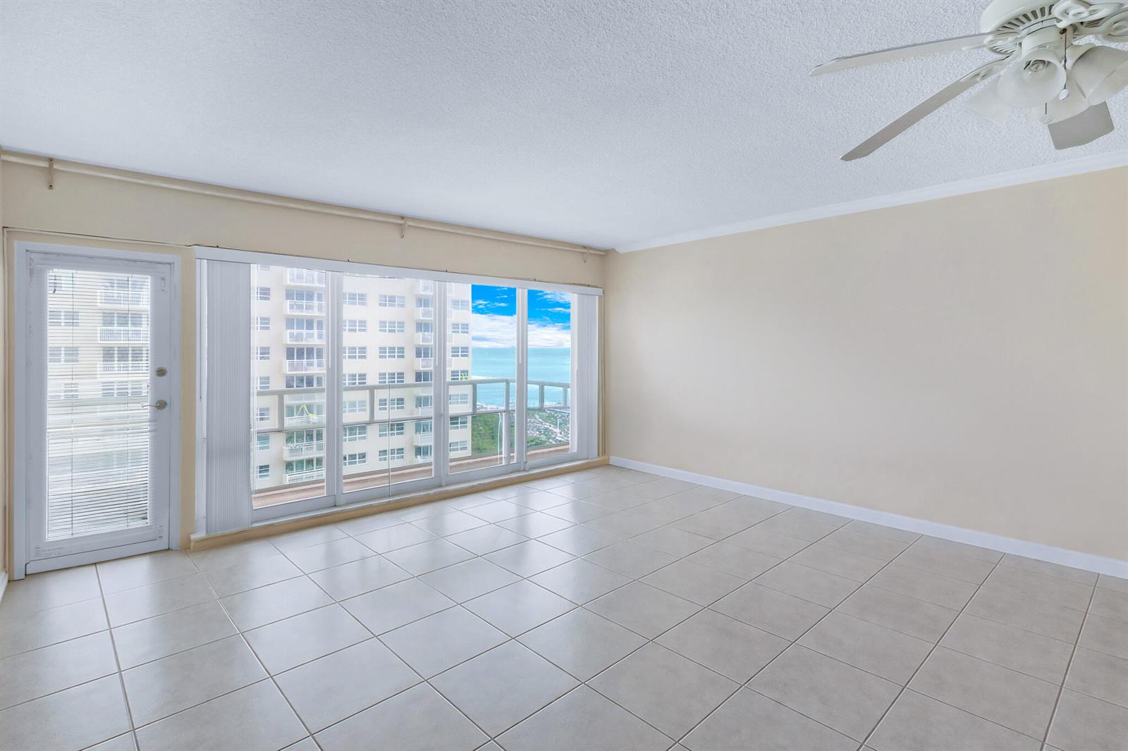 An empty room with light-colored tile flooring, a ceiling fan, and a balcony with ocean views — 111 N Pompano Beach Boulevard # 1507, Pompano Beach FL 33062, POMPANO BEACH, FL