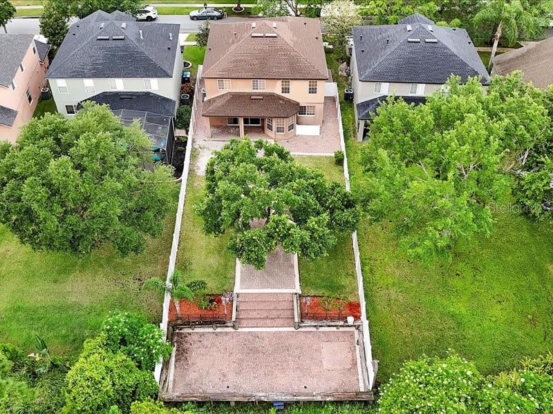An aerial view shows a tan house with a brick patio and a large backyard — 10233 SEROTINA COURT, ORLANDO, FL