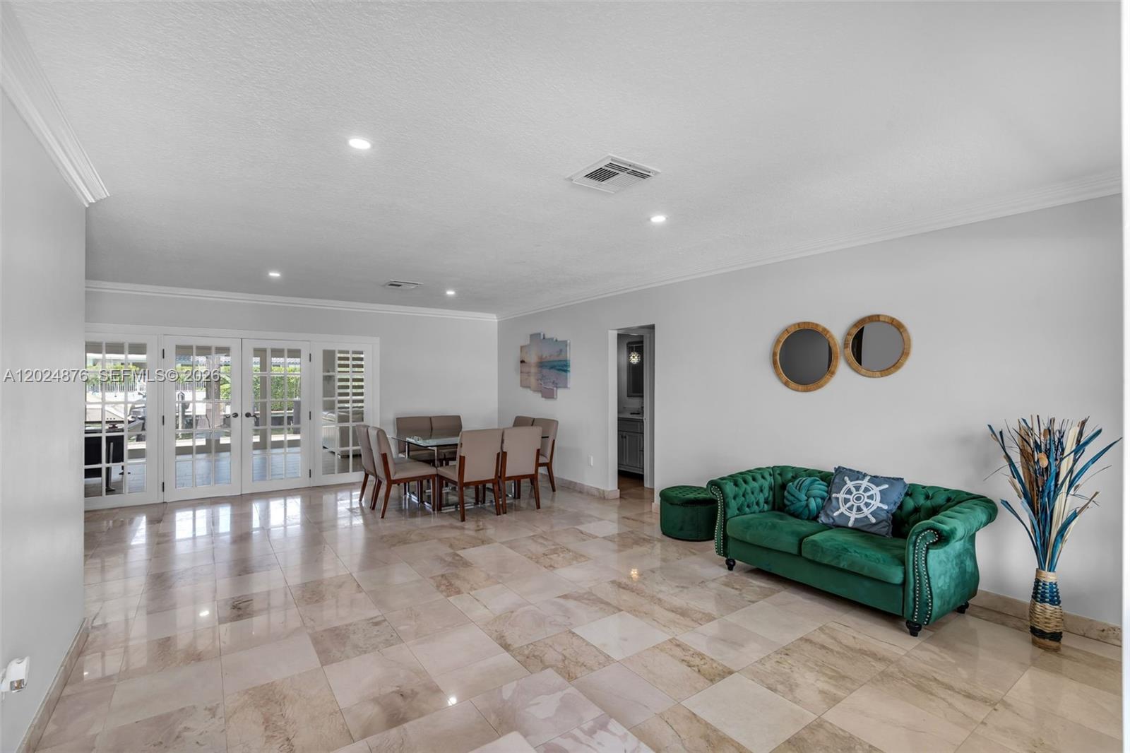 A spacious room features light tile flooring, a green velvet sofa, and a dining area — 1261 NE 82nd St, Miami FL 33138, MIAMI, FL