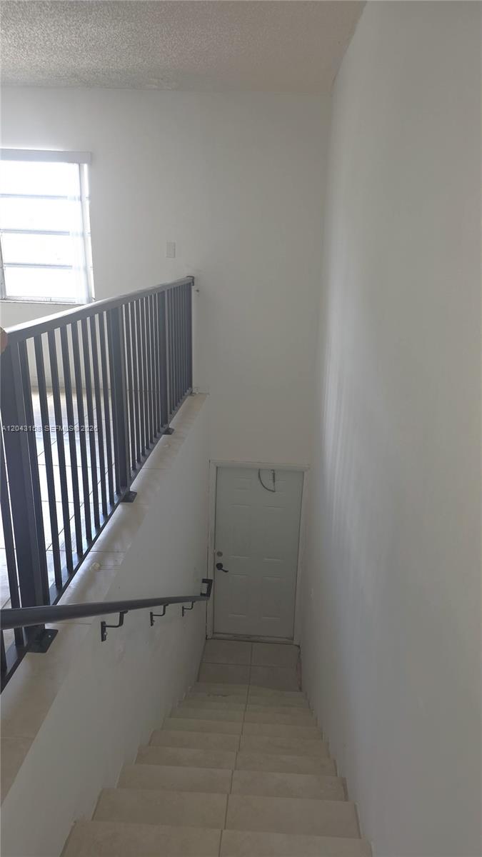 A staircase with tiled steps and a metal railing leads down to a white door — 3519 SW 17th Ter # 3519, Miami FL 33145, MIAMI, FL