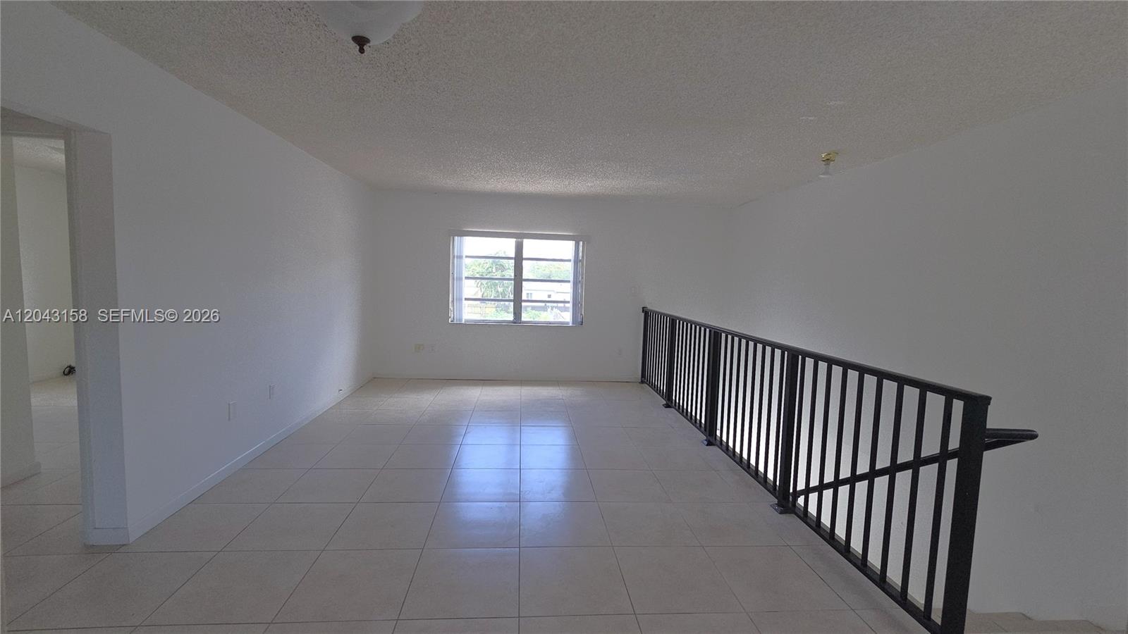 An upstairs landing features white tile flooring, white walls, and a black metal railing — 3519 SW 17th Ter # 3519, Miami FL 33145, MIAMI, FL
