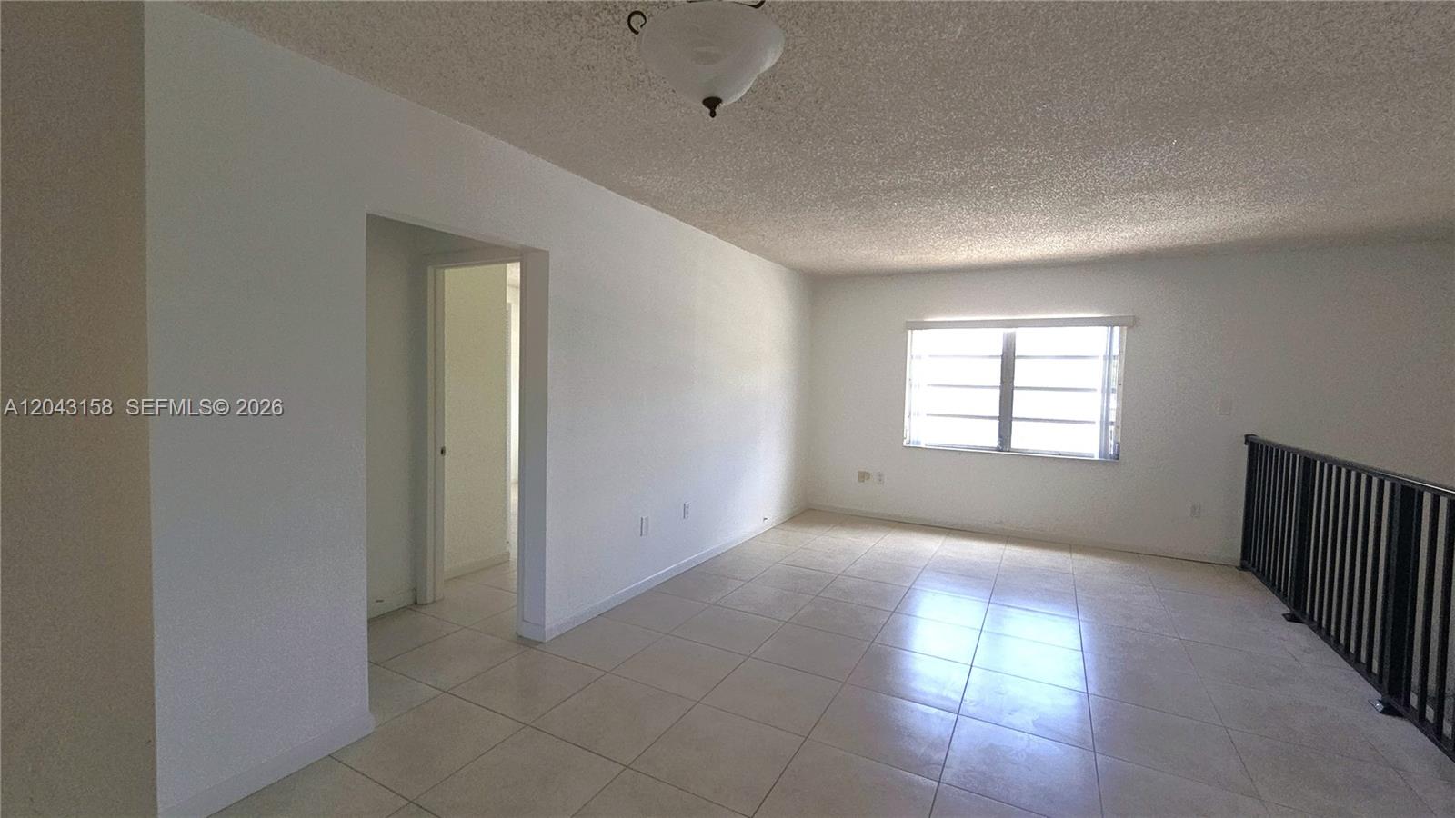An empty room features white walls, light-colored tile flooring, a textured ceiling, and a window — 3519 SW 17th Ter # 3519, Miami FL 33145, MIAMI, FL