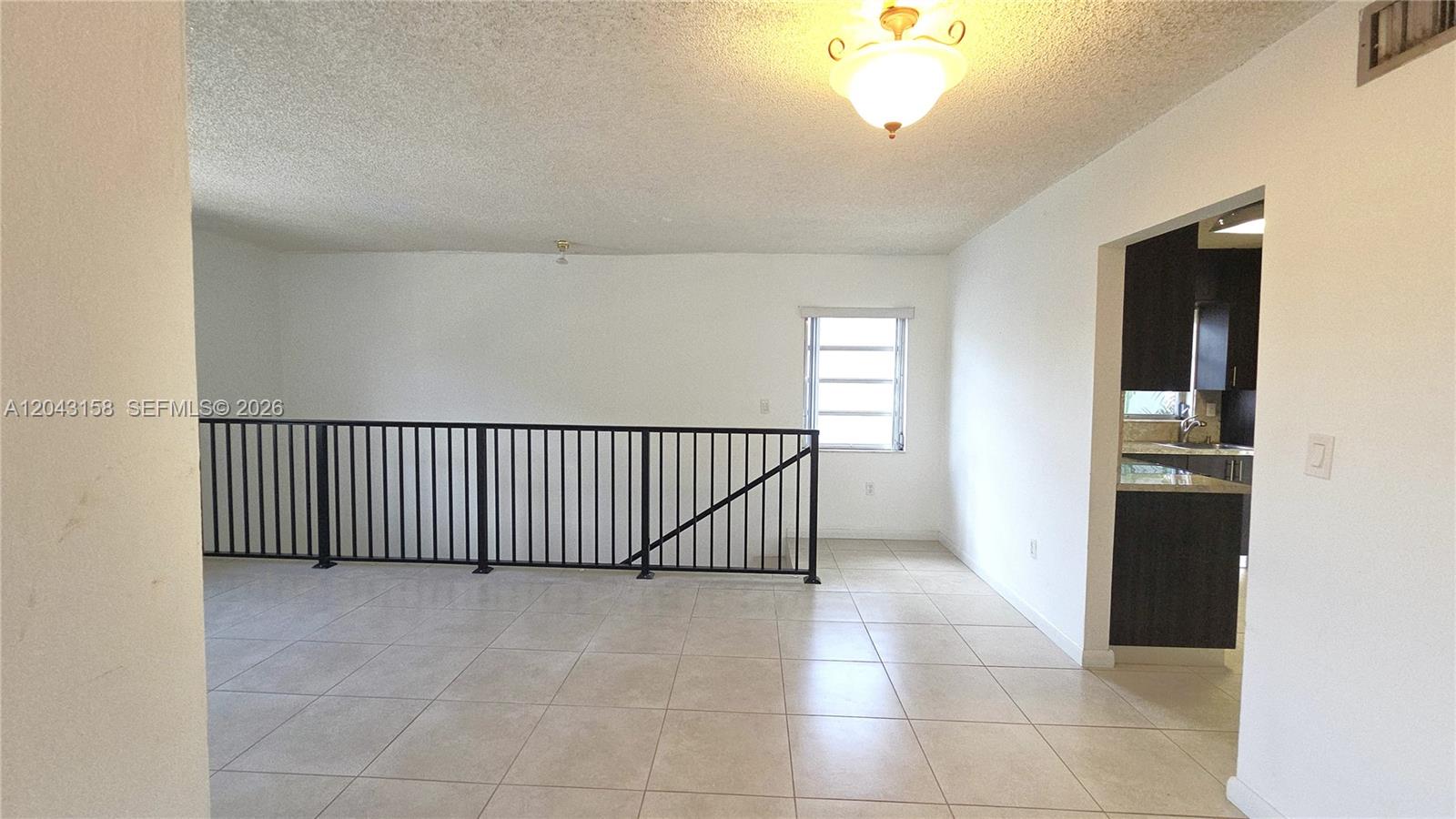 This room features light-colored tile flooring, white walls, and a black metal stair railing — 3519 SW 17th Ter # 3519, Miami FL 33145, MIAMI, FL