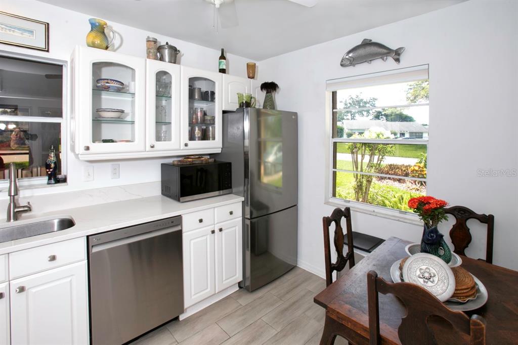 A kitchen with white cabinets, stainless steel appliances, and a small dining table by a window — 6504 HERITAGE LANE UNIT 99, BRADENTON, FL