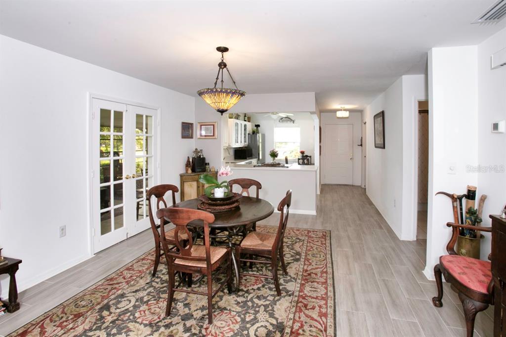 A dining area features a round wooden table, patterned rug, and a stained-glass pendant light — 6504 HERITAGE LANE UNIT 99, BRADENTON, FL