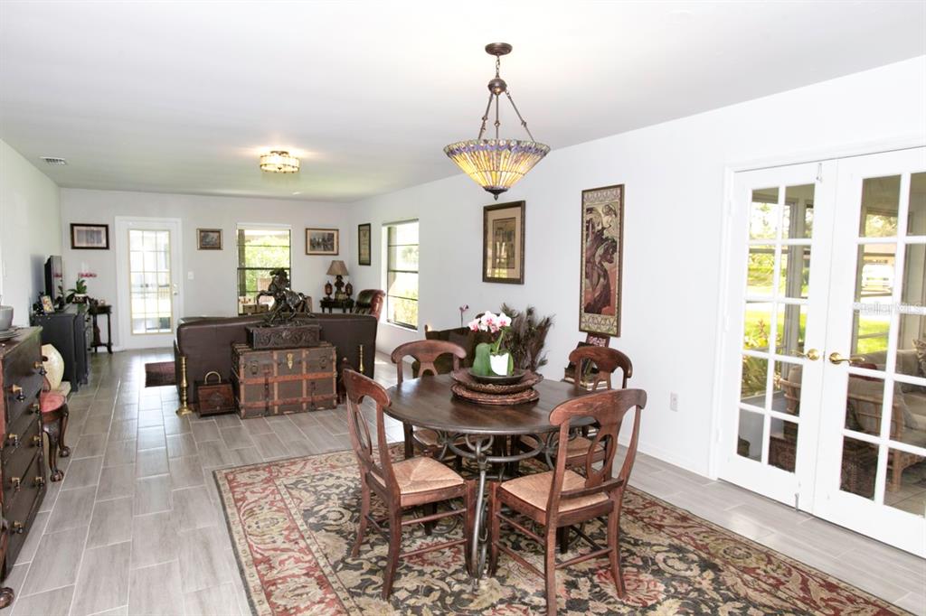 A dining area with a round wooden table and chairs sits on a patterned rug — 6504 HERITAGE LANE UNIT 99, BRADENTON, FL