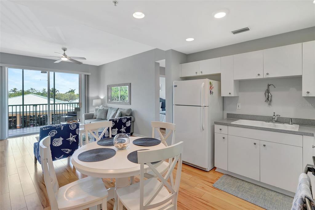 A kitchen and dining area with white cabinets, a round table, and a balcony view — 2090 MATECUMBE KEY ROAD UNIT 1207, PUNTA GORDA, FL